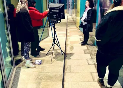 Lady being filmed outside against hoarding